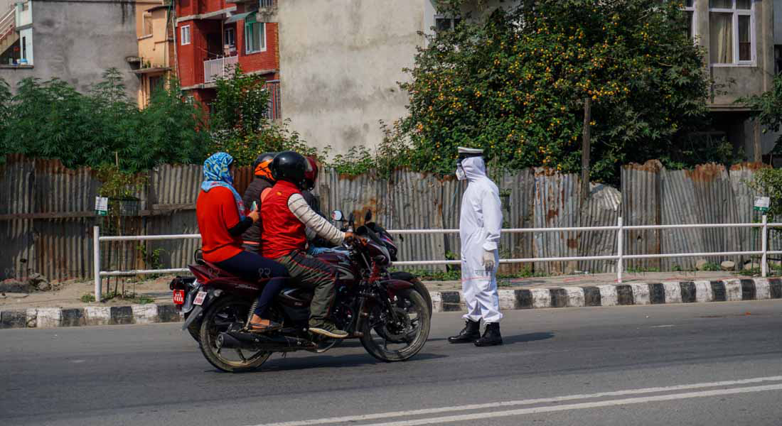 काठमाडौंको टेकुमा पीपीई लगाएर सवारीसाधन जाँचमा खटिएका ट्राफिक प्रहरी । तस्बिर : सुनील प्रधान/बाह्रखरी