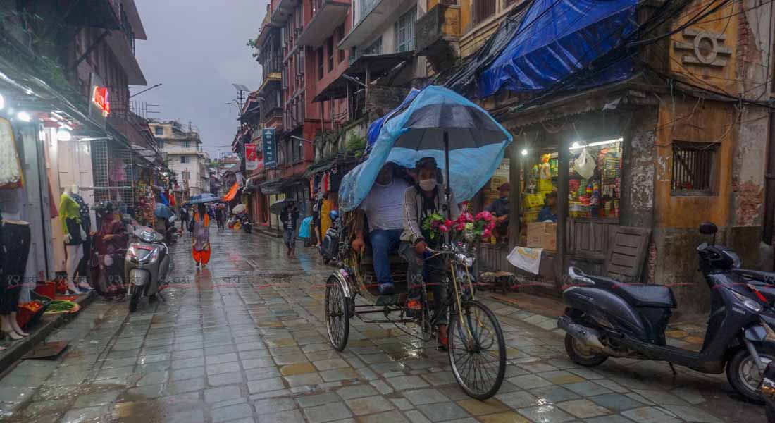 बिहीबार साँझ पानी परिरहेको बेला काठमाडौको मरु टोलबाट आफ्नो ग्राहकलाई रिक्सामा गन्तव्यमा लग्दै रिक्साचालक । तस्बिरः सुनिल प्रधान