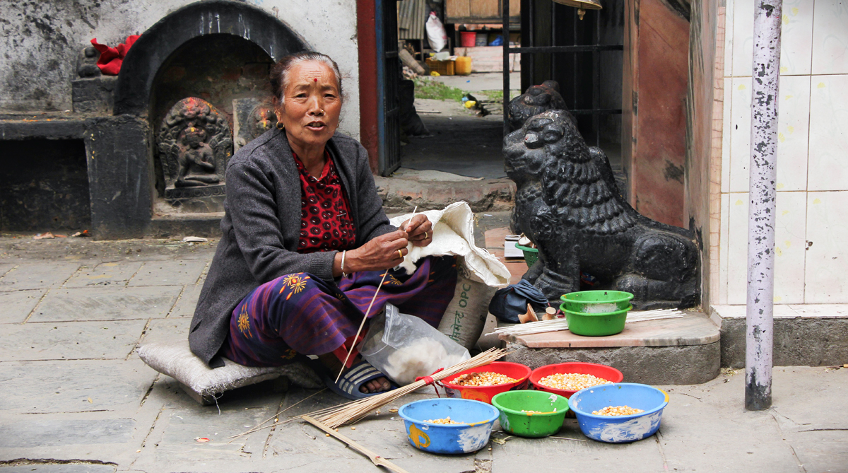 काठमाडौंको भद्रकालीमा परेवाका लागि चारो बेच्दै एक महिला । तस्बिर : हरिशजंग क्षेत्री