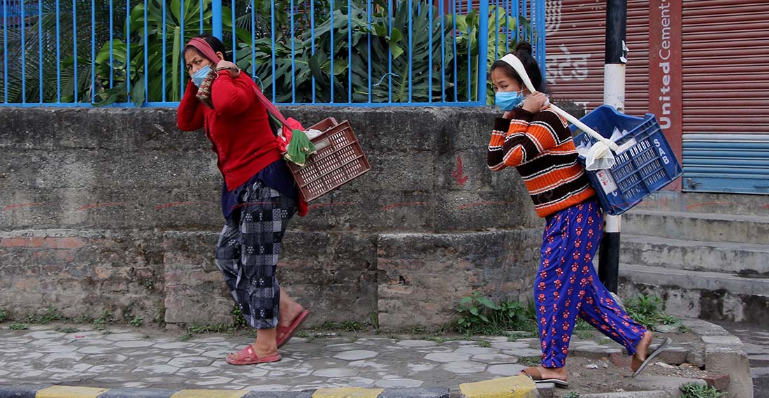 निषेधाज्ञामा काठमाडौंको धोबीखोलामा तरकारी बेचेर घर फर्किँदै दुई महिला । तस्बिर : हरिशजंग क्षेत्री